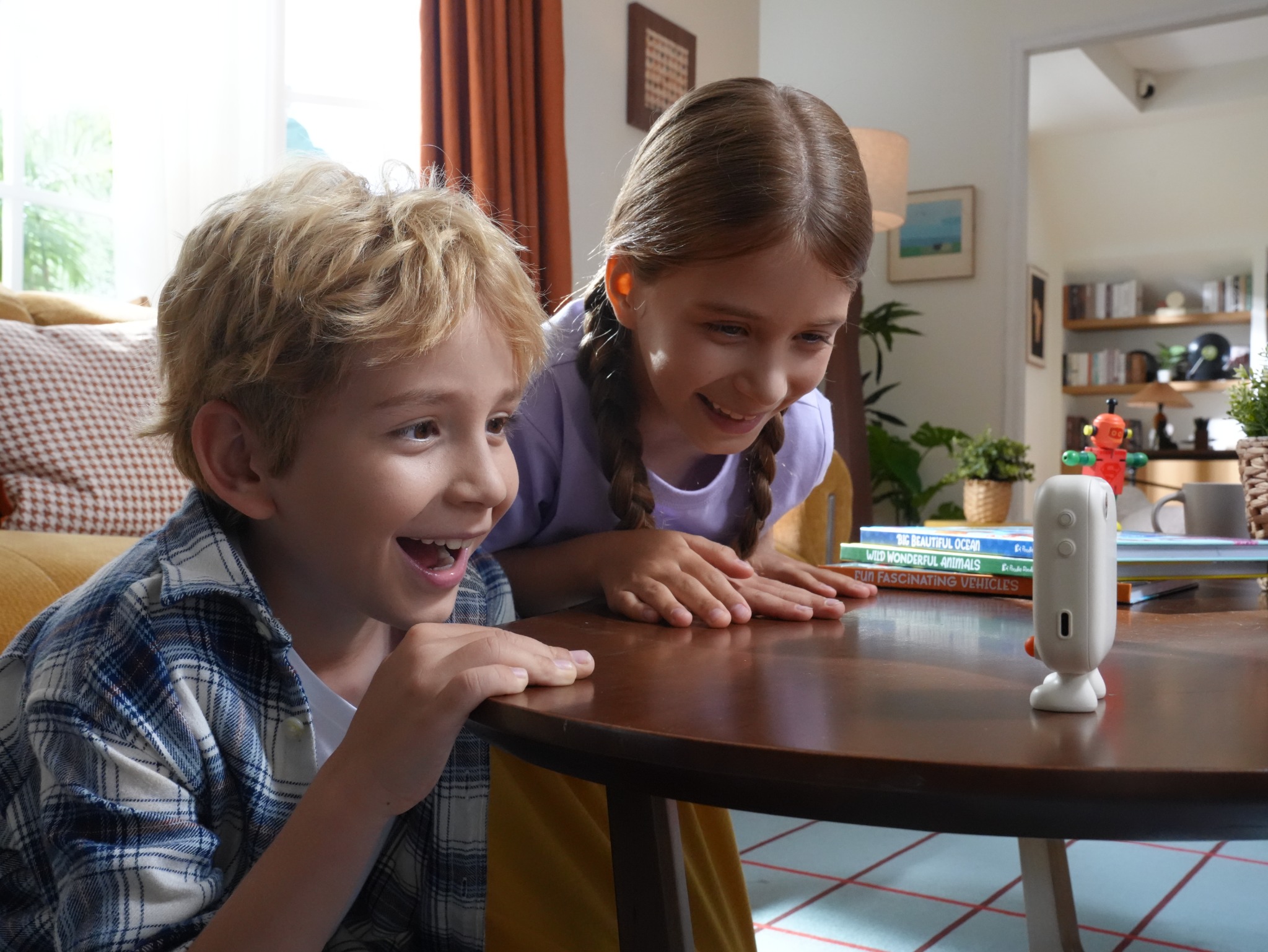 Two children leaning forward excitedly toward Puddibear on the table